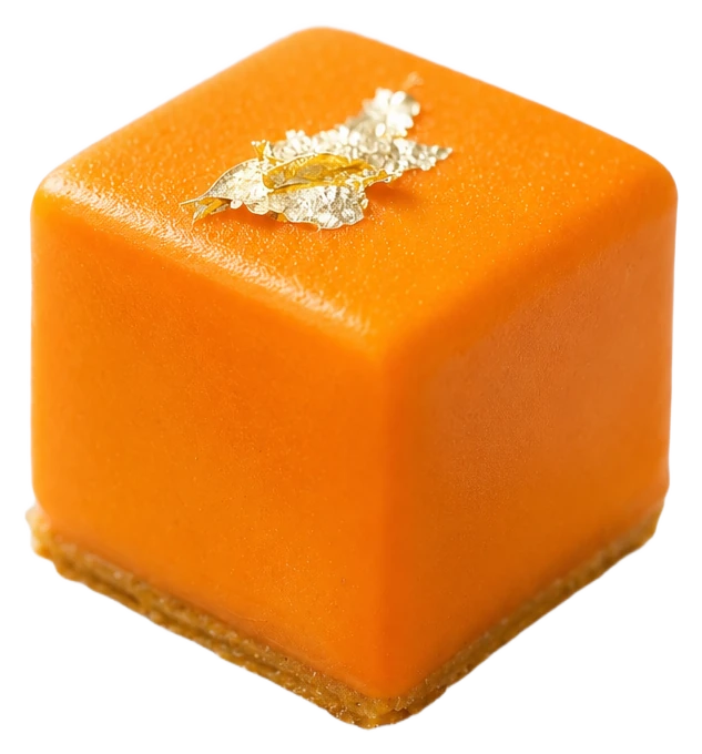 Cube à glaçage orange velours sur socle de sablé, marqué d'un éclat de feuille d'or