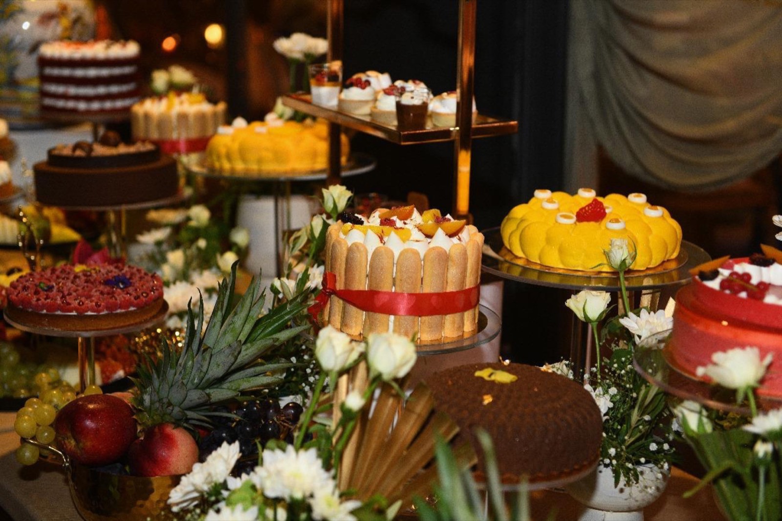 Table sucrée en enfilade : charlotte à ruban rouge, entremets au miroir jaune, red velvet et tarte aux framboises
