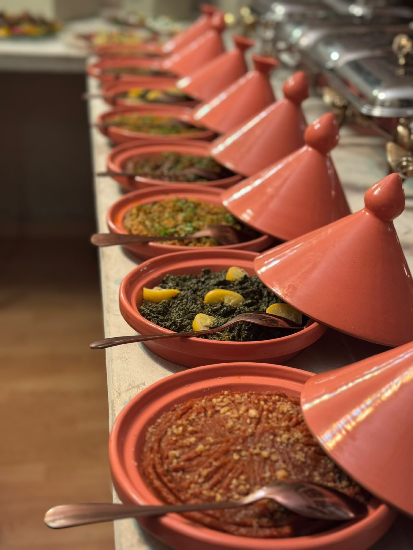 Enfilade de mini-tagines de terre cuite garnies de salades cuites marocaines, chapeaux posés de biais