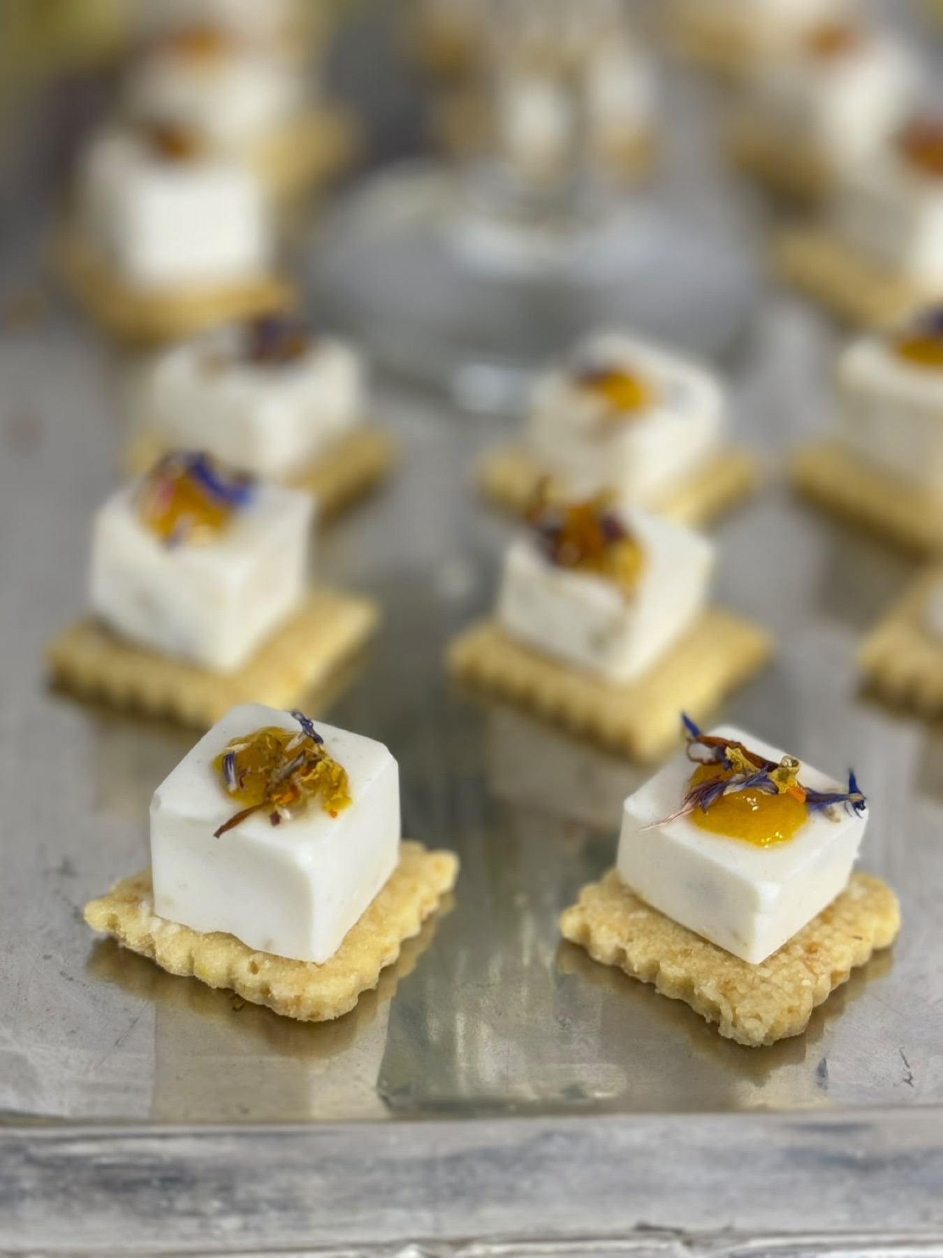 Bouchées froides : cube de mousse blanche sur sablé cannelé, marmelade d'agrume et fleur séchée bleue