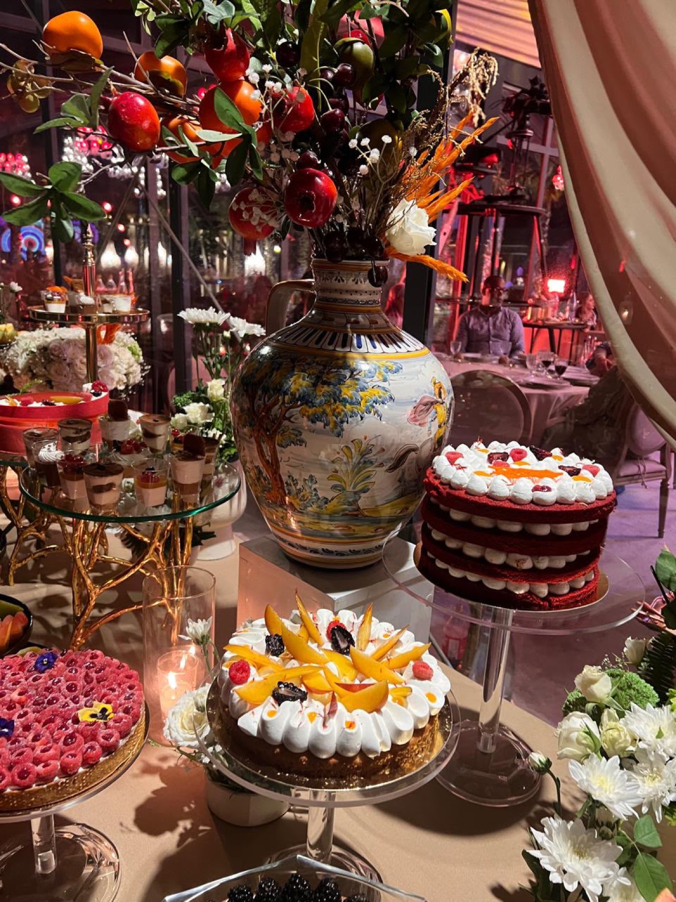Table sucrée dressée en soirée : red velvet à étages, entremets aux fruits jaunes, tarte aux framboises et verrines