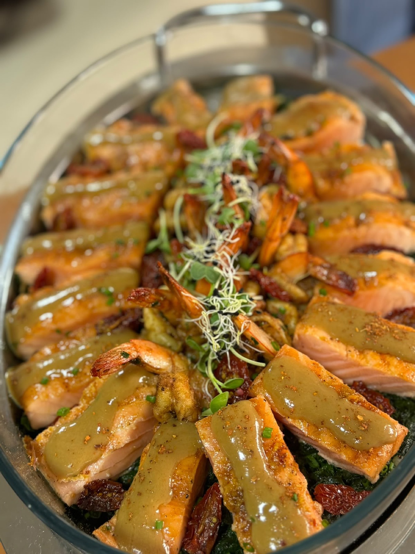 Plat de verre monté en couronne : pavés de saumon nappés d'une sauce blonde, gambas entières et tomates confites